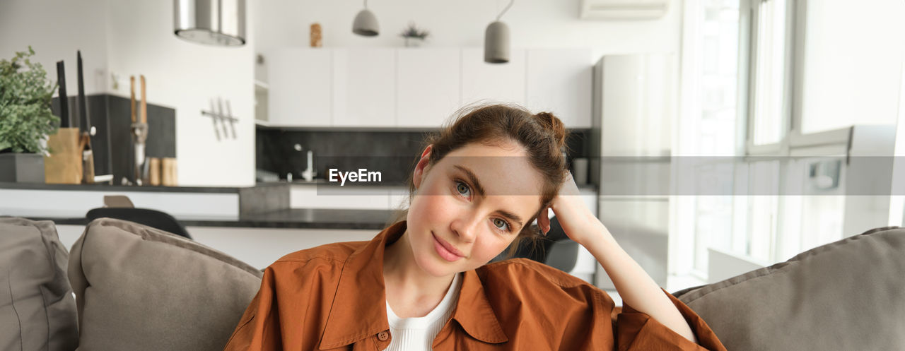 young woman looking away while standing at home