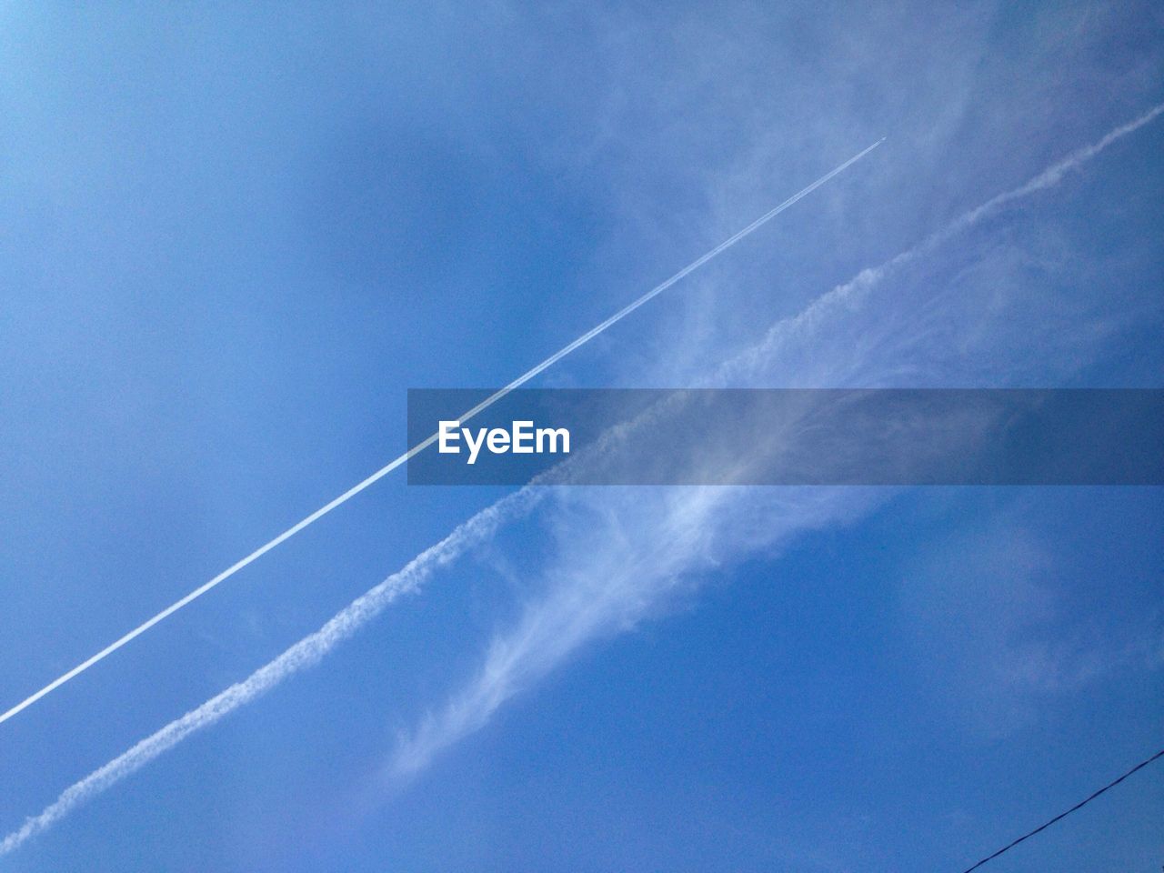 LOW ANGLE VIEW OF VAPOR TRAILS IN BLUE SKY