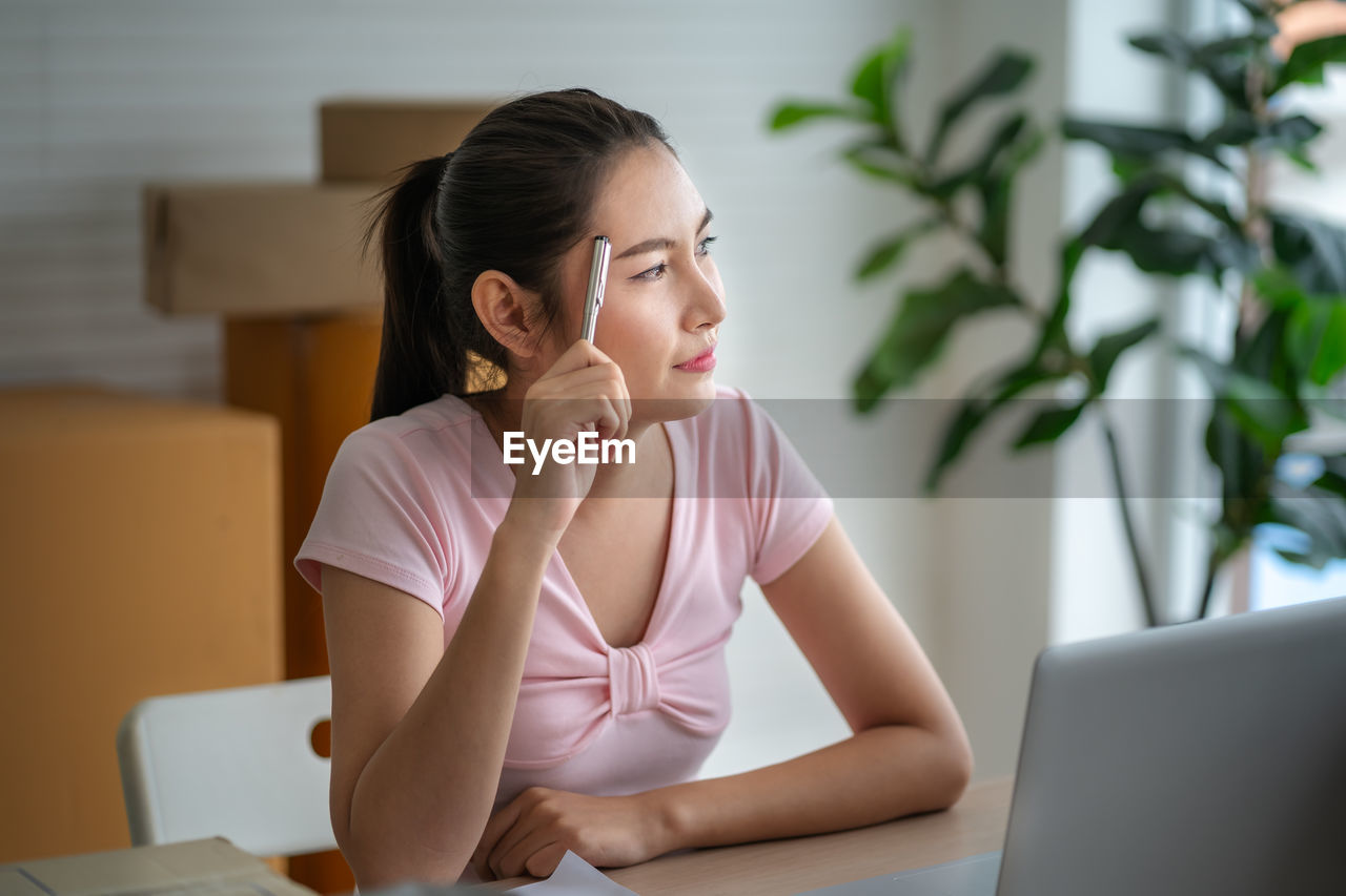 Thoughtful woman looking away while sitting at office