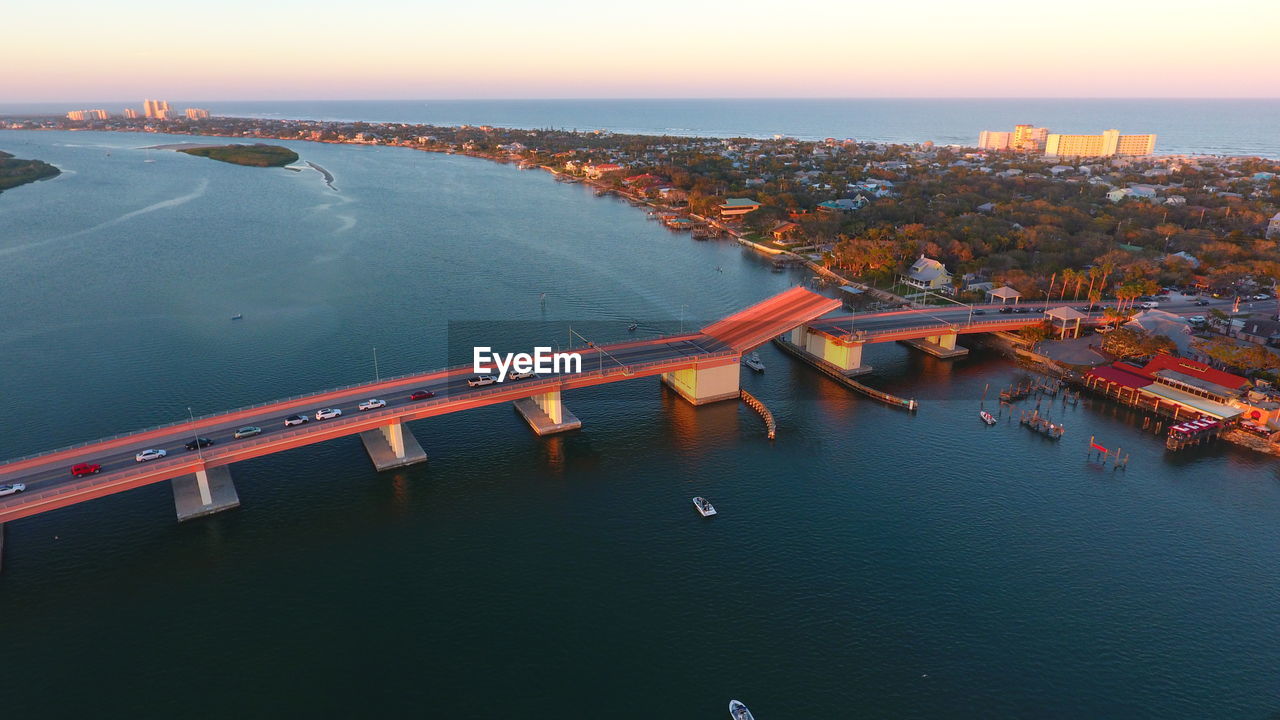 Aerial view of bridge over river against sky at sunset