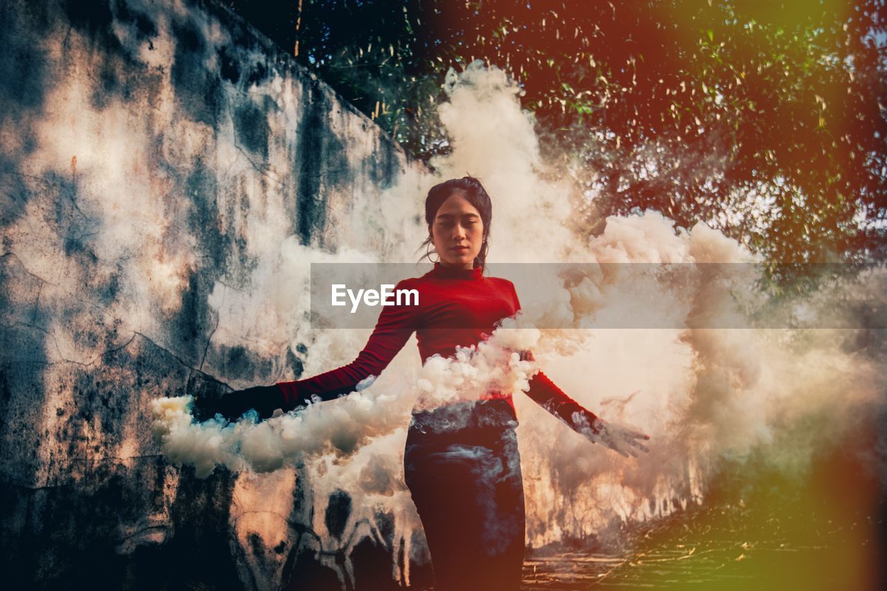 Young woman standing amidst smoke in forest