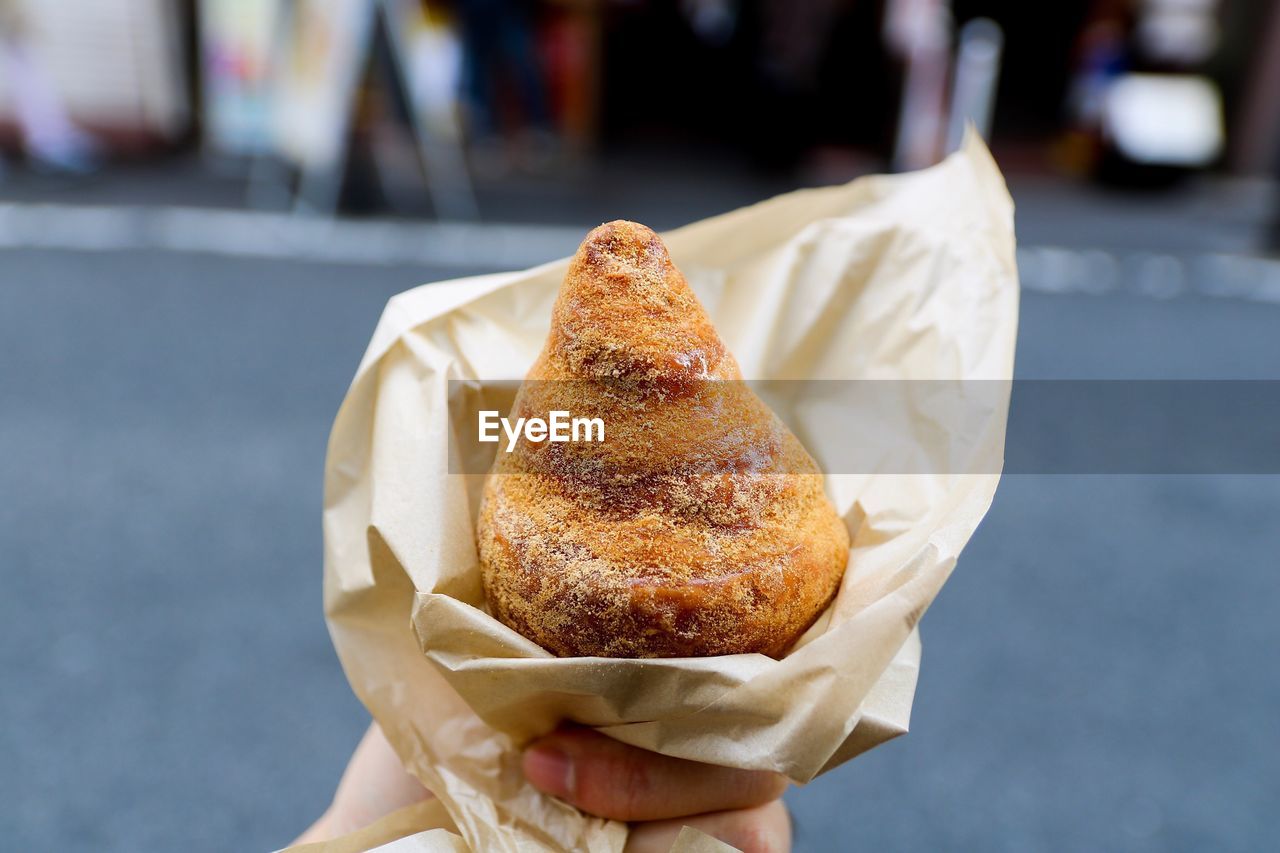 Close-up of human hand holding snack in city