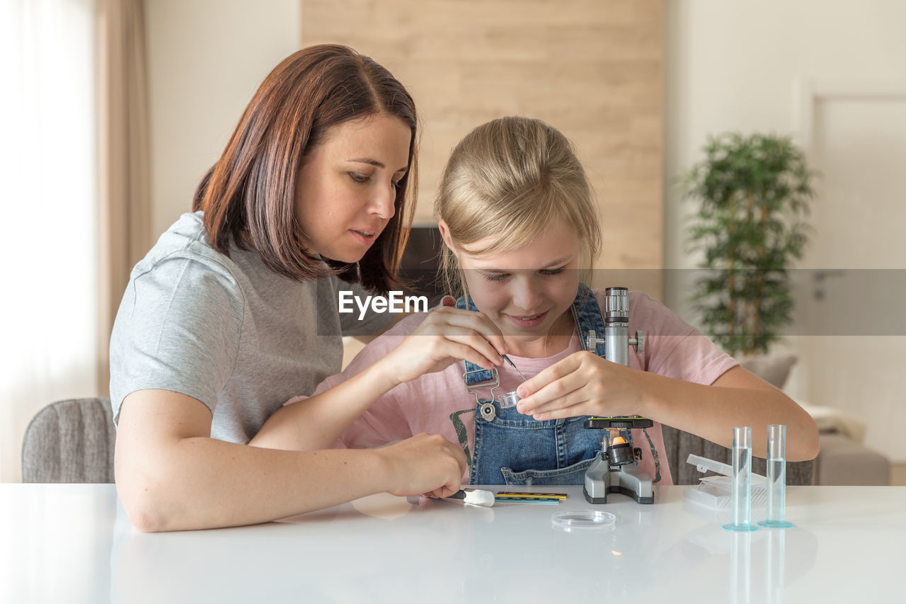 Mother helping daughter in science project at home