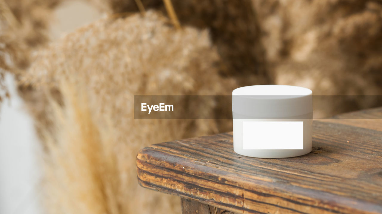 Mockup of a white jar of face and body skin cream on wooden tabletop. friendly product.