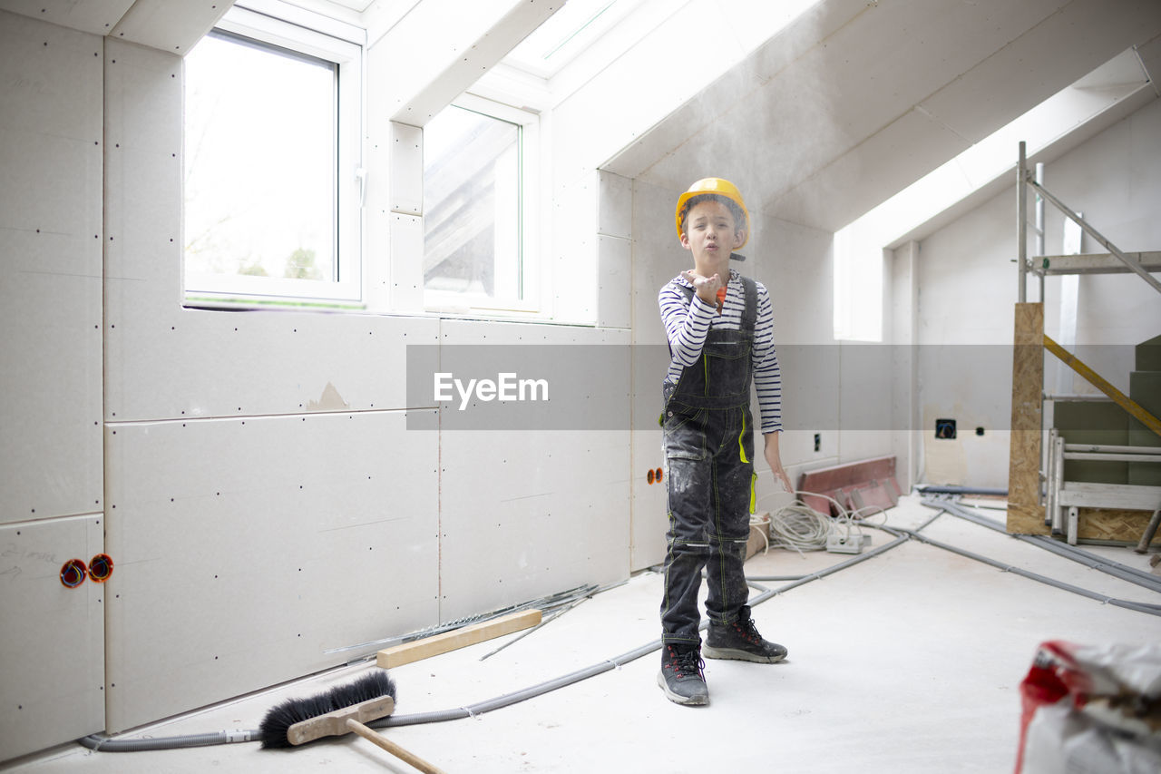 portrait of young man standing against wall at home