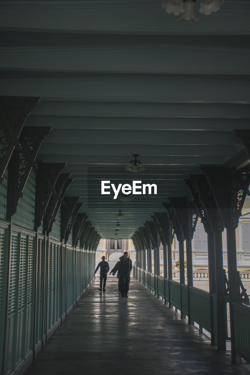 Rear view of people walking on footpath amidst buildings