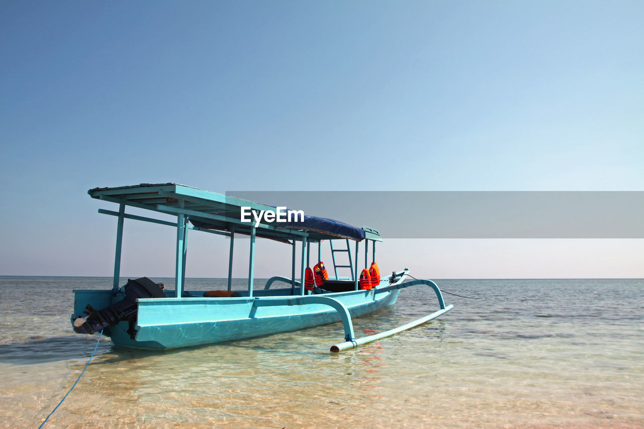 Boat on shore against clear blue sky