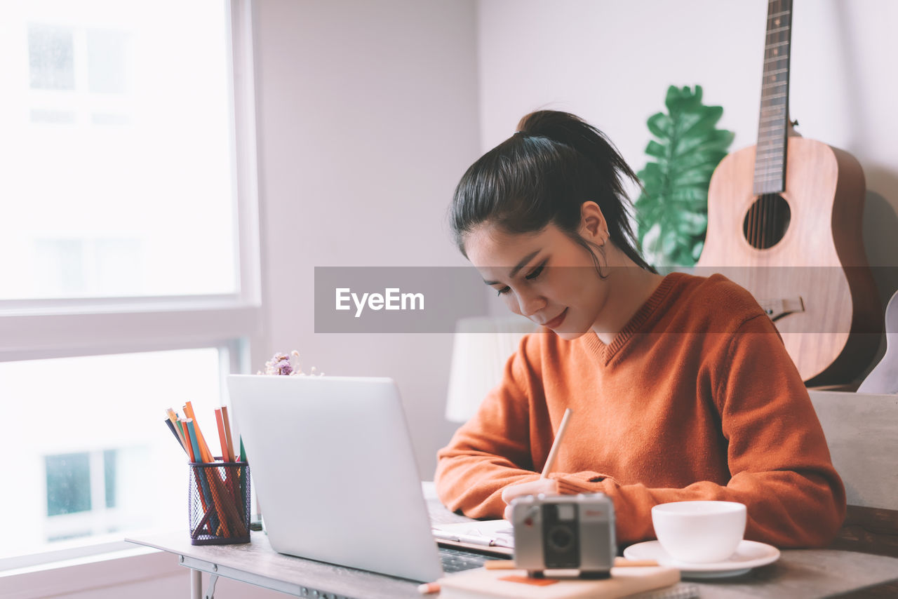 Woman using laptop while sitting on table
