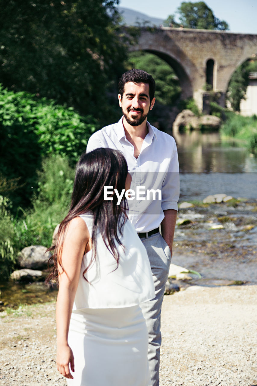 Couple looking at each other while walking against river