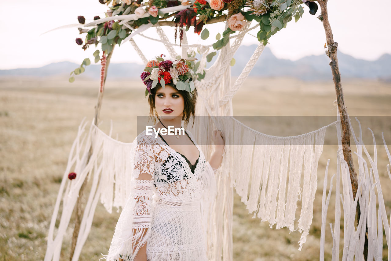 portrait of smiling young woman standing by plants on field