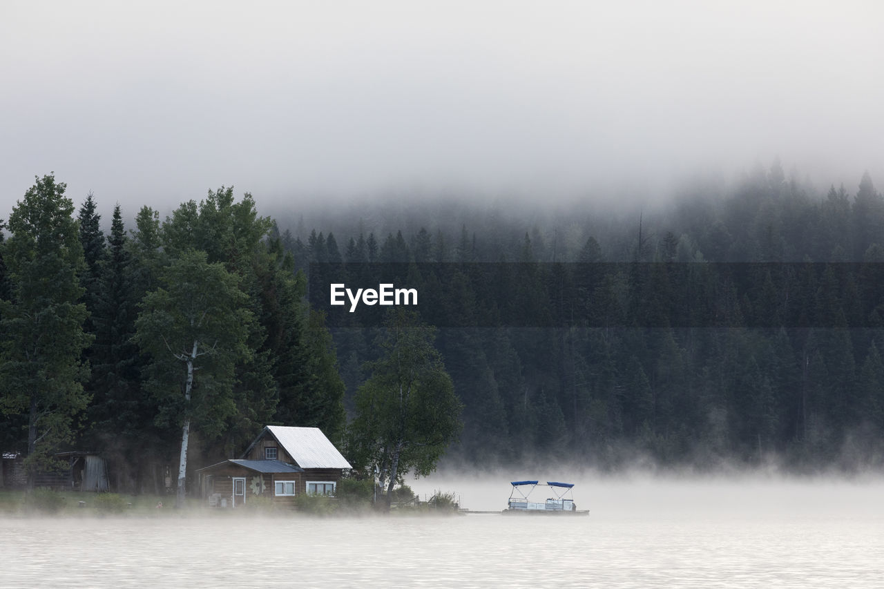 Wooden cabin on lake shore on foggy morning in british columbia