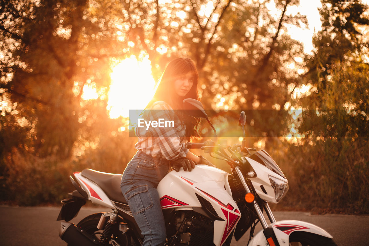 Portrait of confident woman sitting on motorcycle on country road