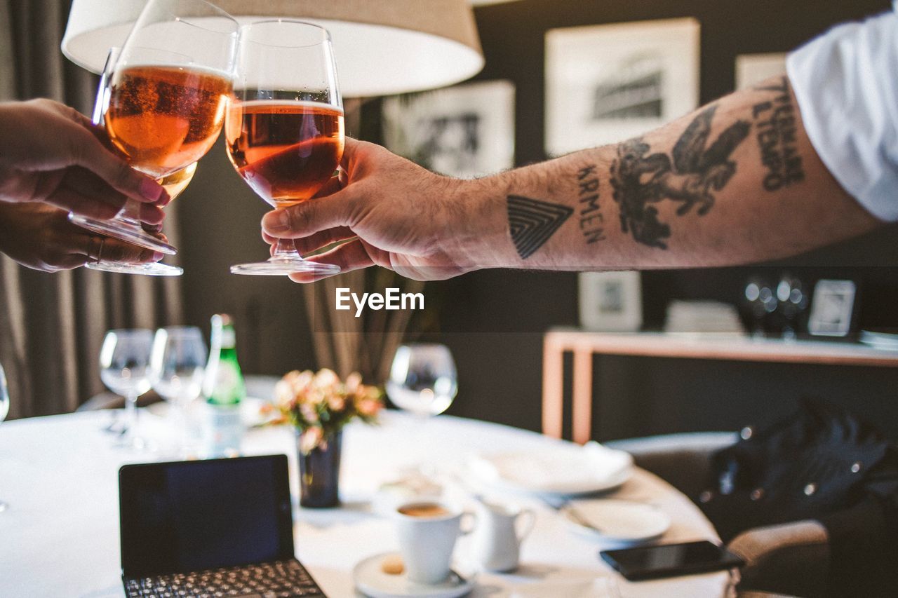 Cropped hands toasting wineglasses at restaurant