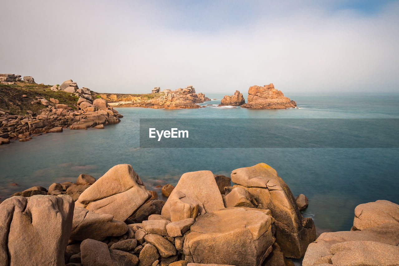 Scenic view of sea by rocks against sky