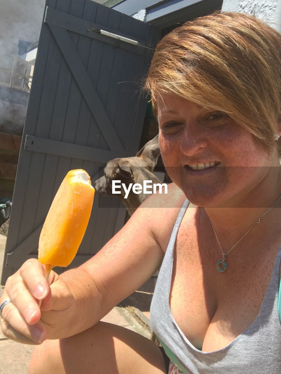 Portrait of woman having popsicles while standing in yard