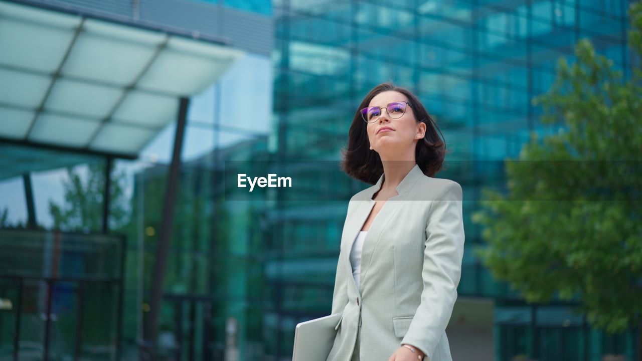 Calm businesswoman looking time on hand watch while going to the work after break