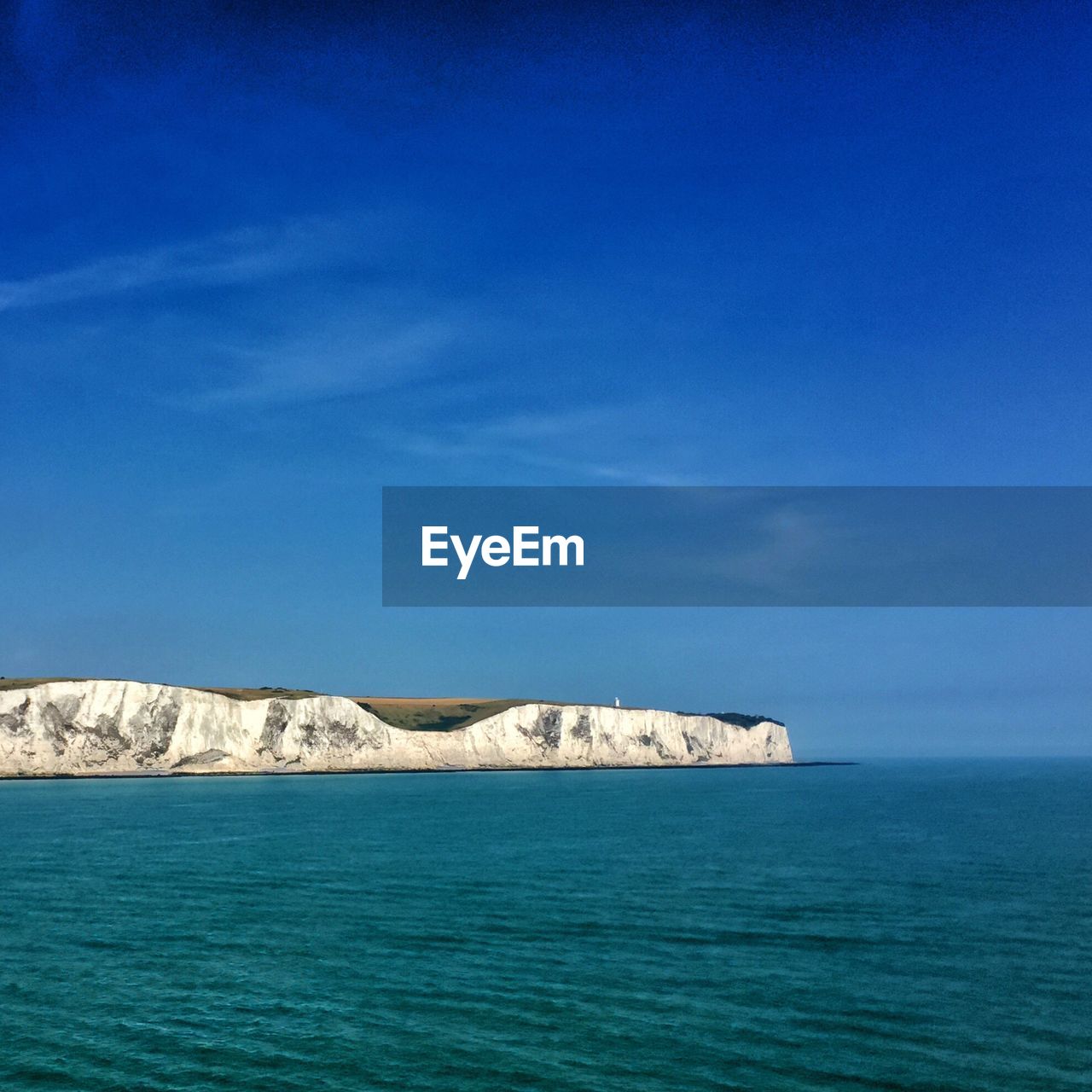 White cliffs of dover by sea against blue sky