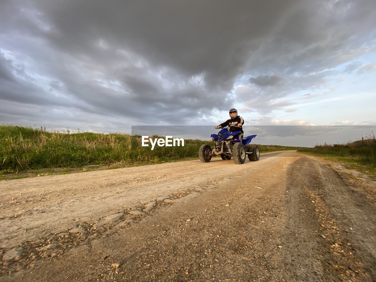 rear view of man riding motor scooter on road against sky