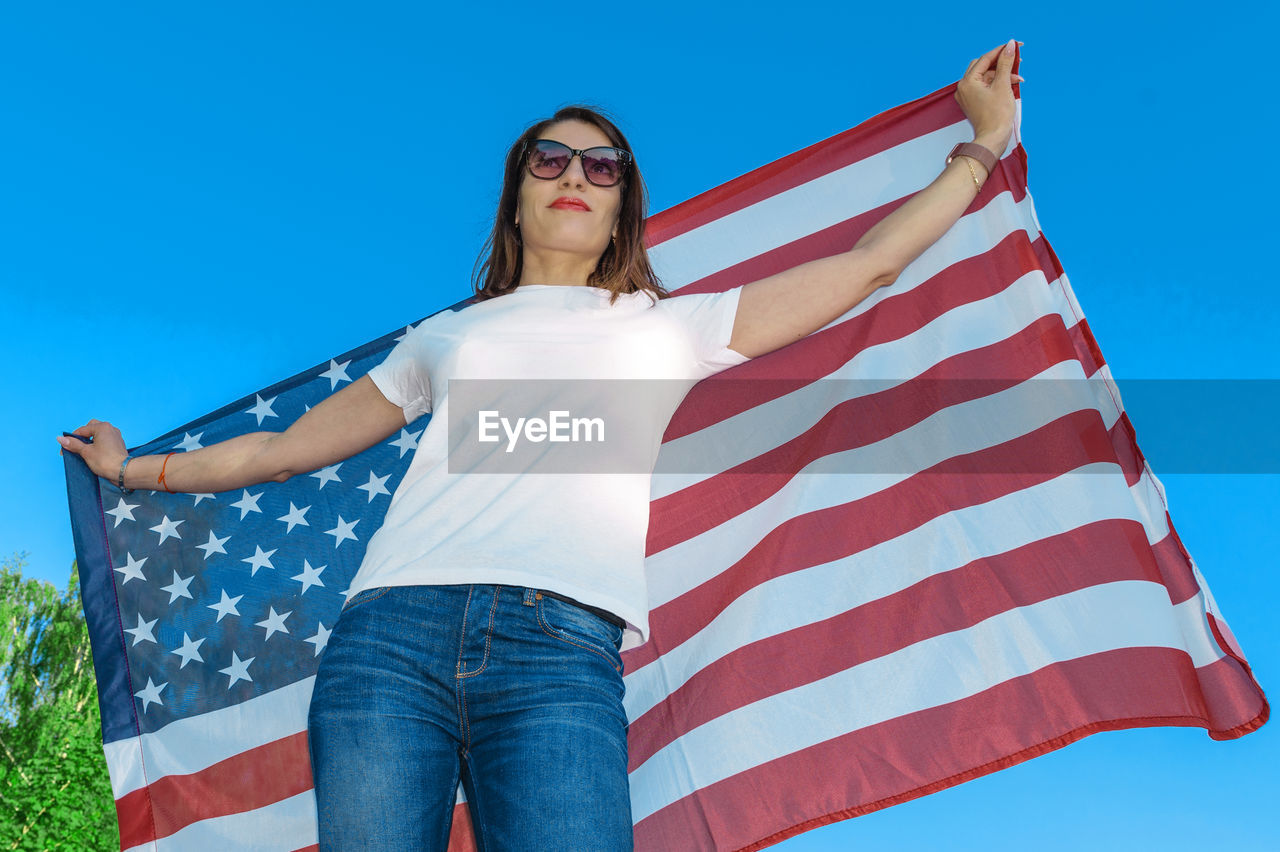 Portrait of smiling pretty young woman holding waving american flag. usa celebrate 4th of july. 