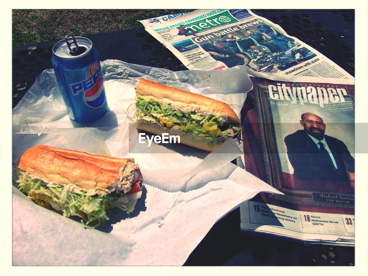 High angle view of sandwiches and cola by newspapers