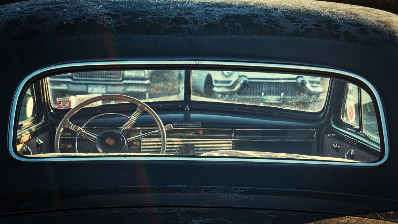 Steering wheel of car seen through rear windshield