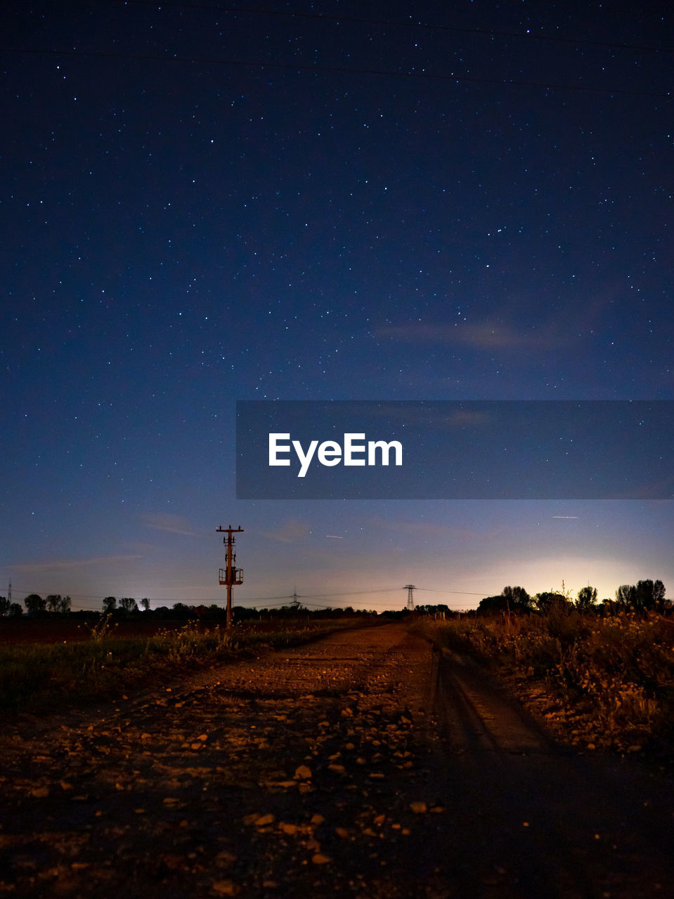 ROAD ON FIELD AGAINST SKY AT NIGHT