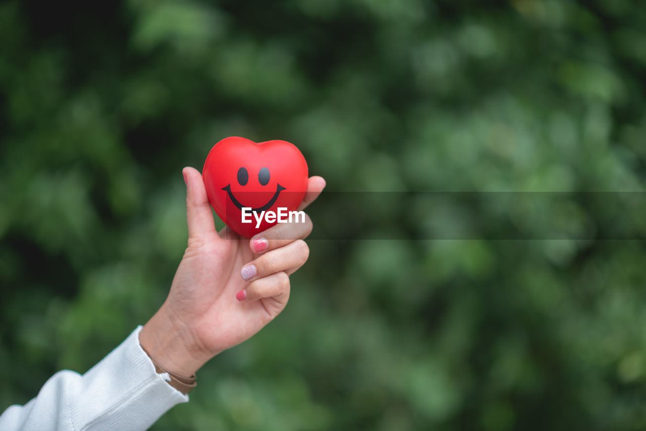 CLOSE-UP OF WOMAN HAND HOLDING HEART SHAPE