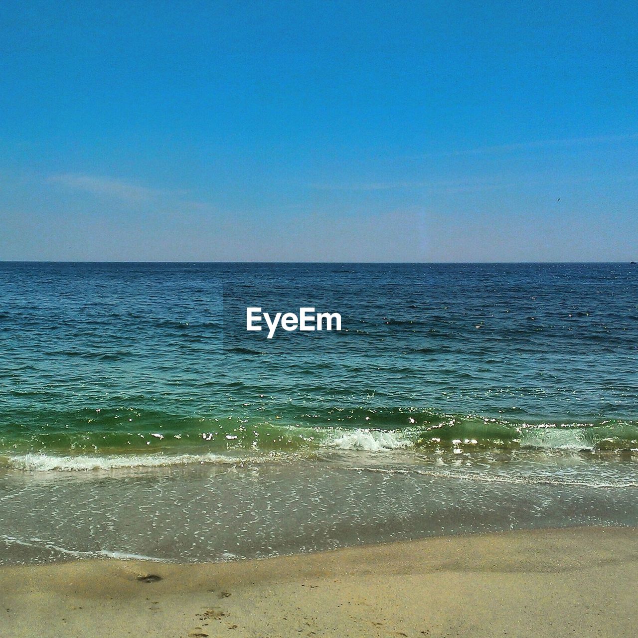 View of calm beach against blue sky