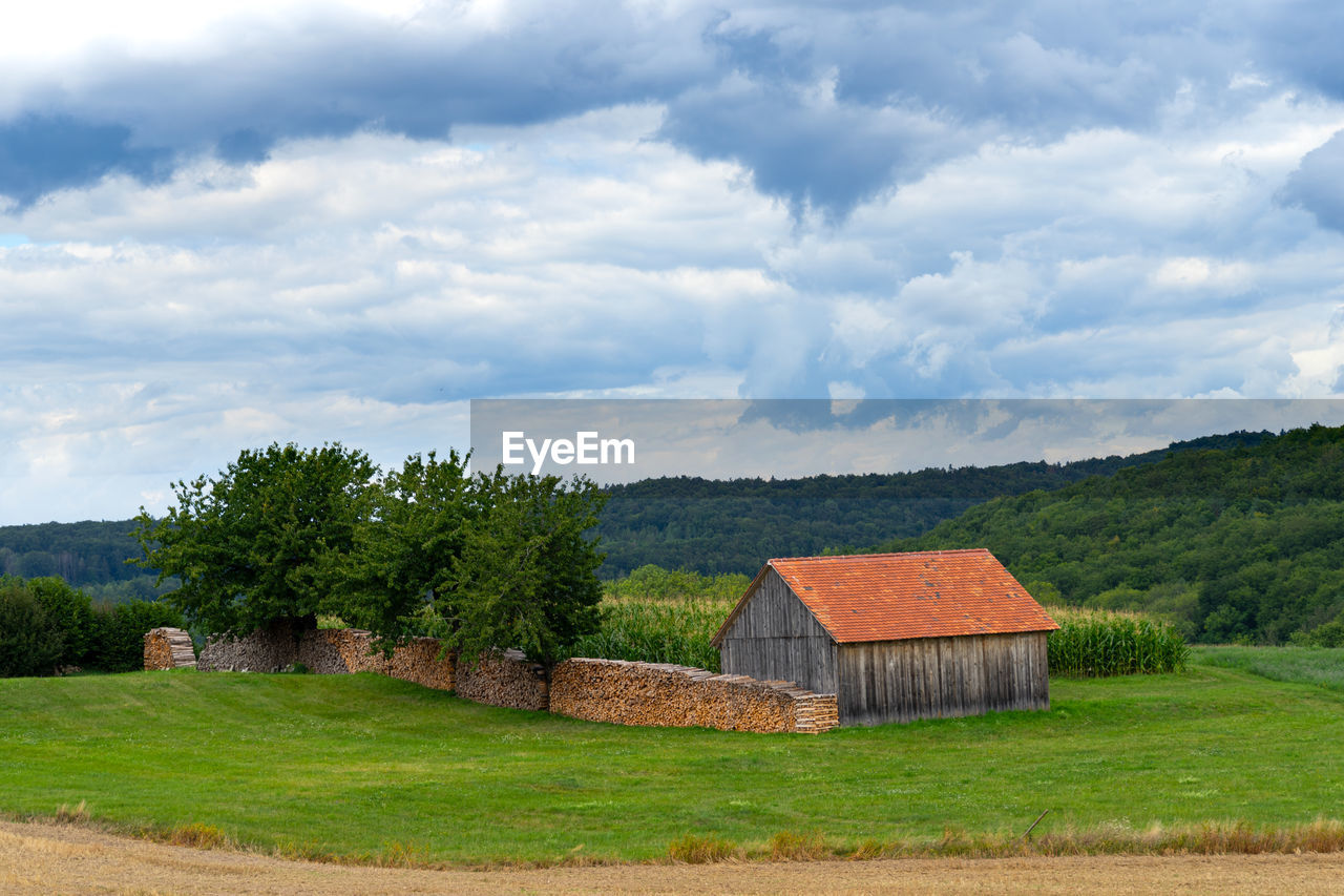 House on field by trees against sky