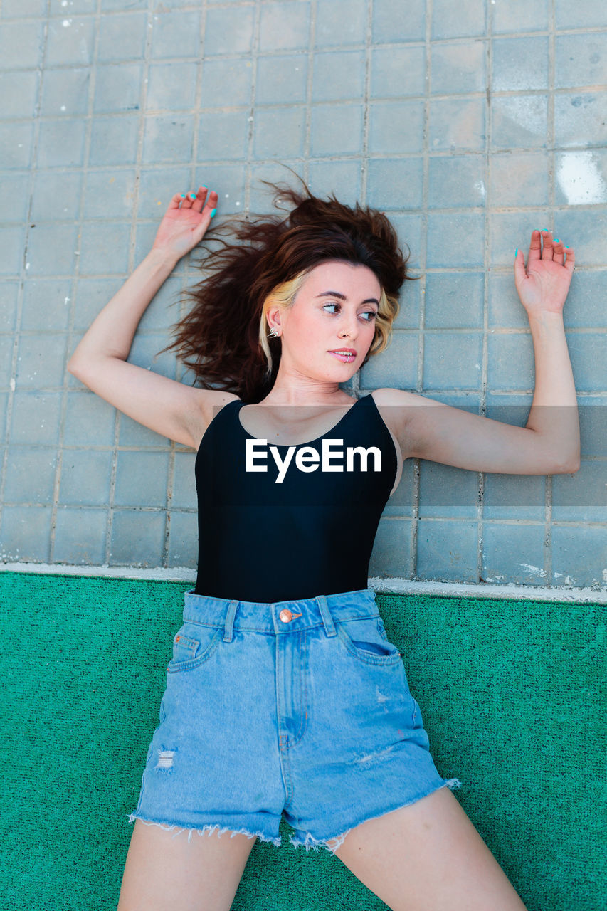 Young depressed woman lying on the ground in a backyard