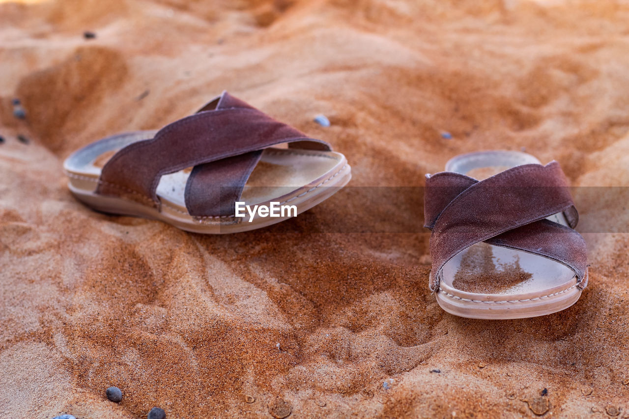 Close-up of shoes on the sand