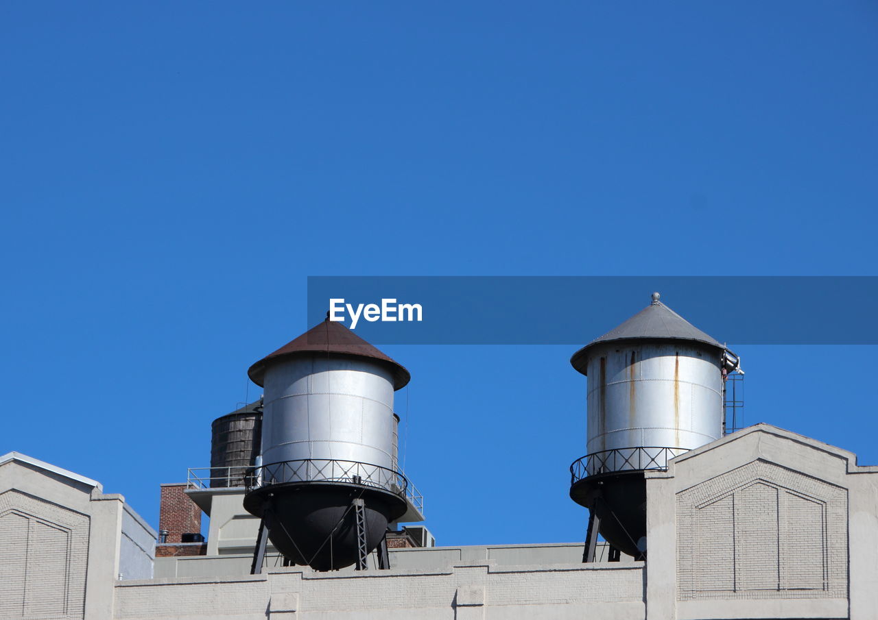 Low angle view of water tower against clear blue sky