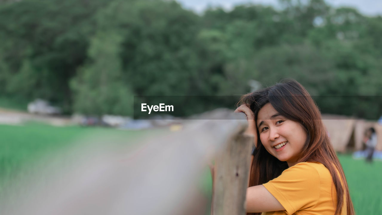 Portrait of smiling young woman standing on field