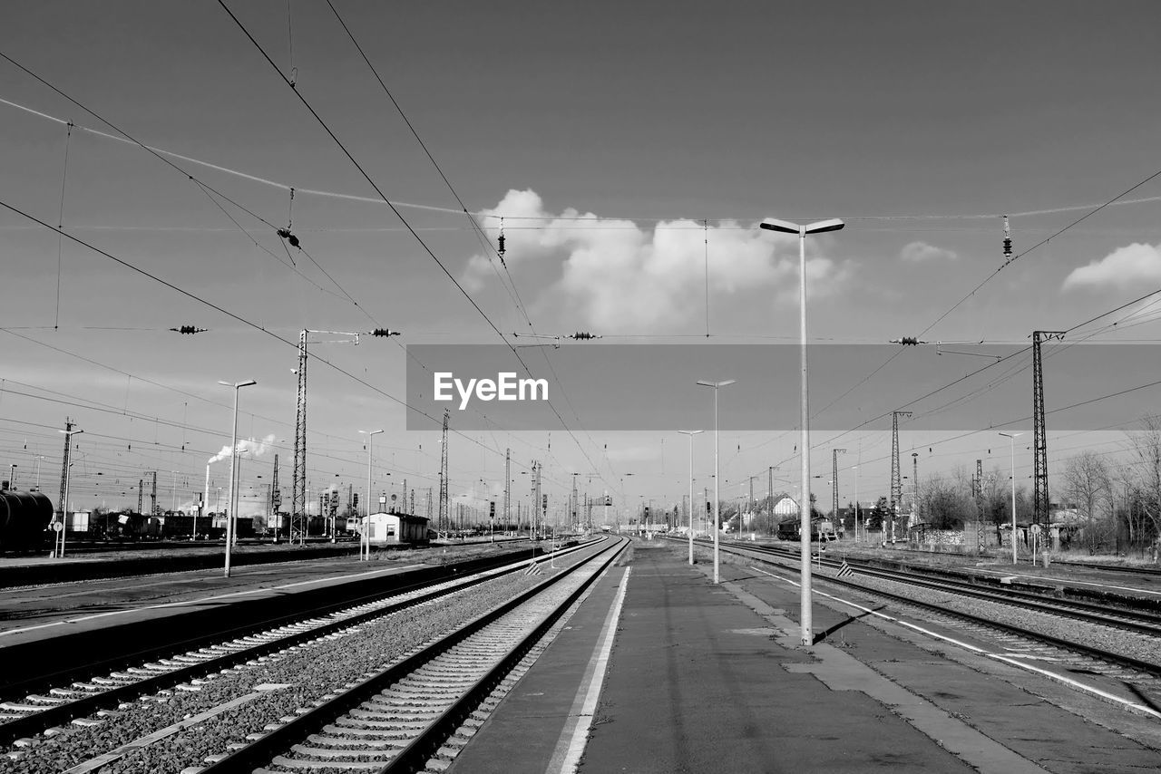 RAILROAD TRACKS BY ELECTRICITY PYLONS AGAINST SKY