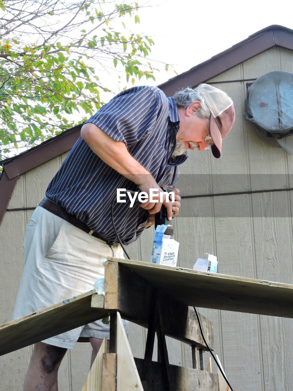 Man drilling wood outdoors