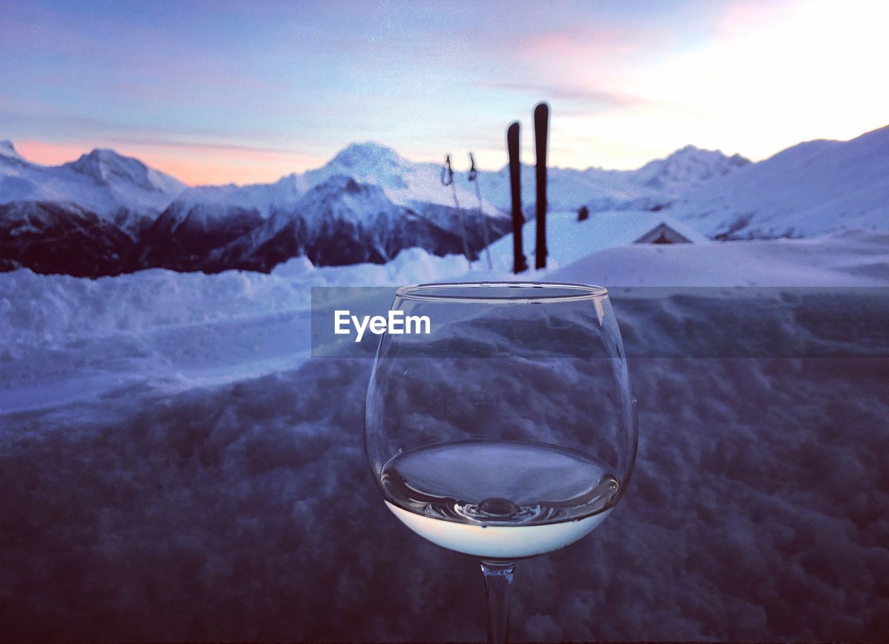 CLOSE-UP OF WINE GLASS AGAINST SNOWCAPPED MOUNTAINS