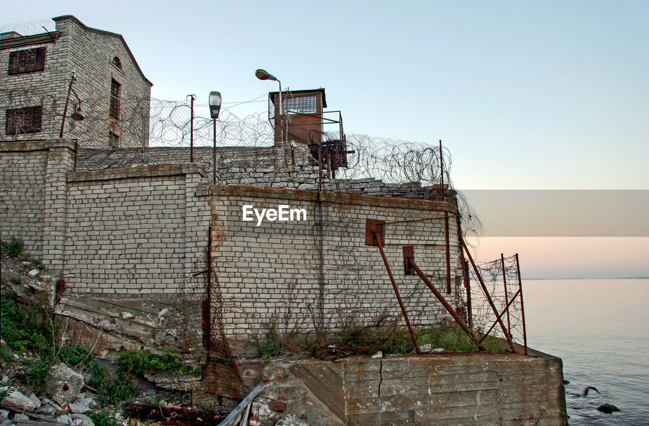 ABANDONED BUILDING BY SEA AGAINST SKY