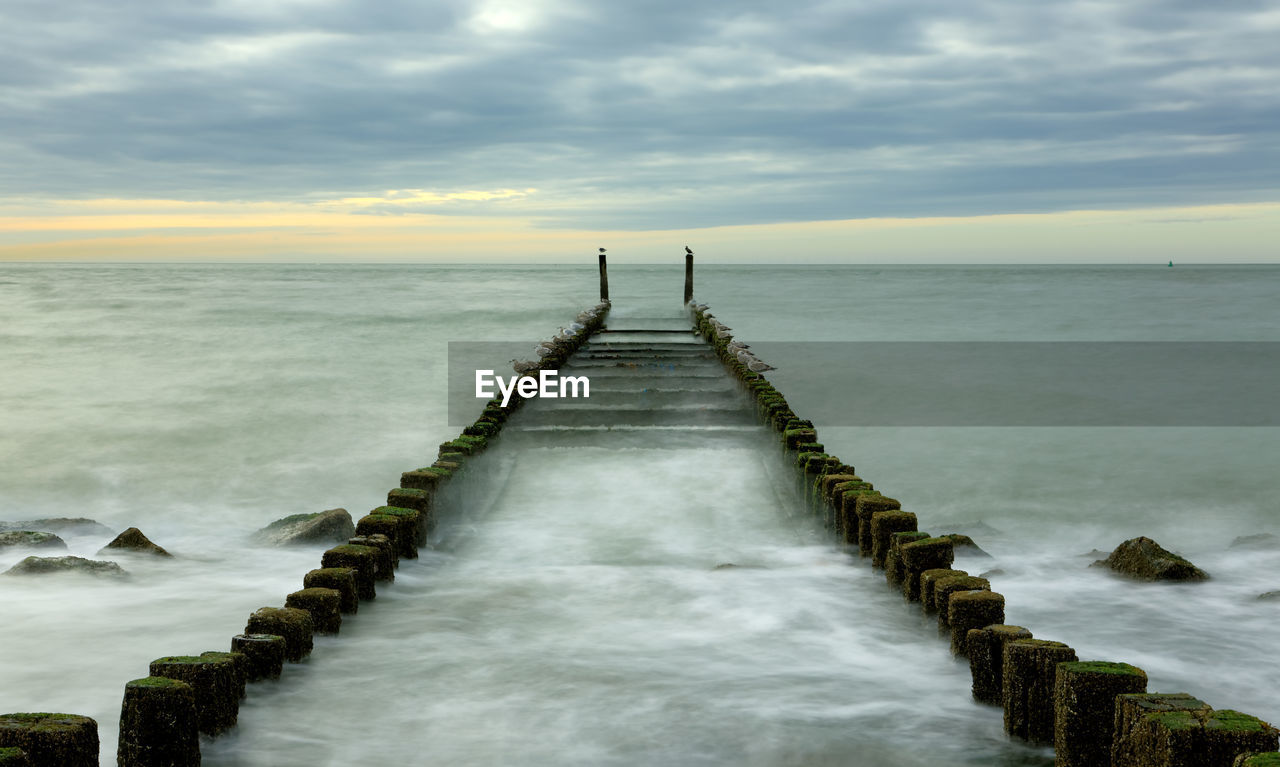 Long exposure image of pier amidst sea against sky