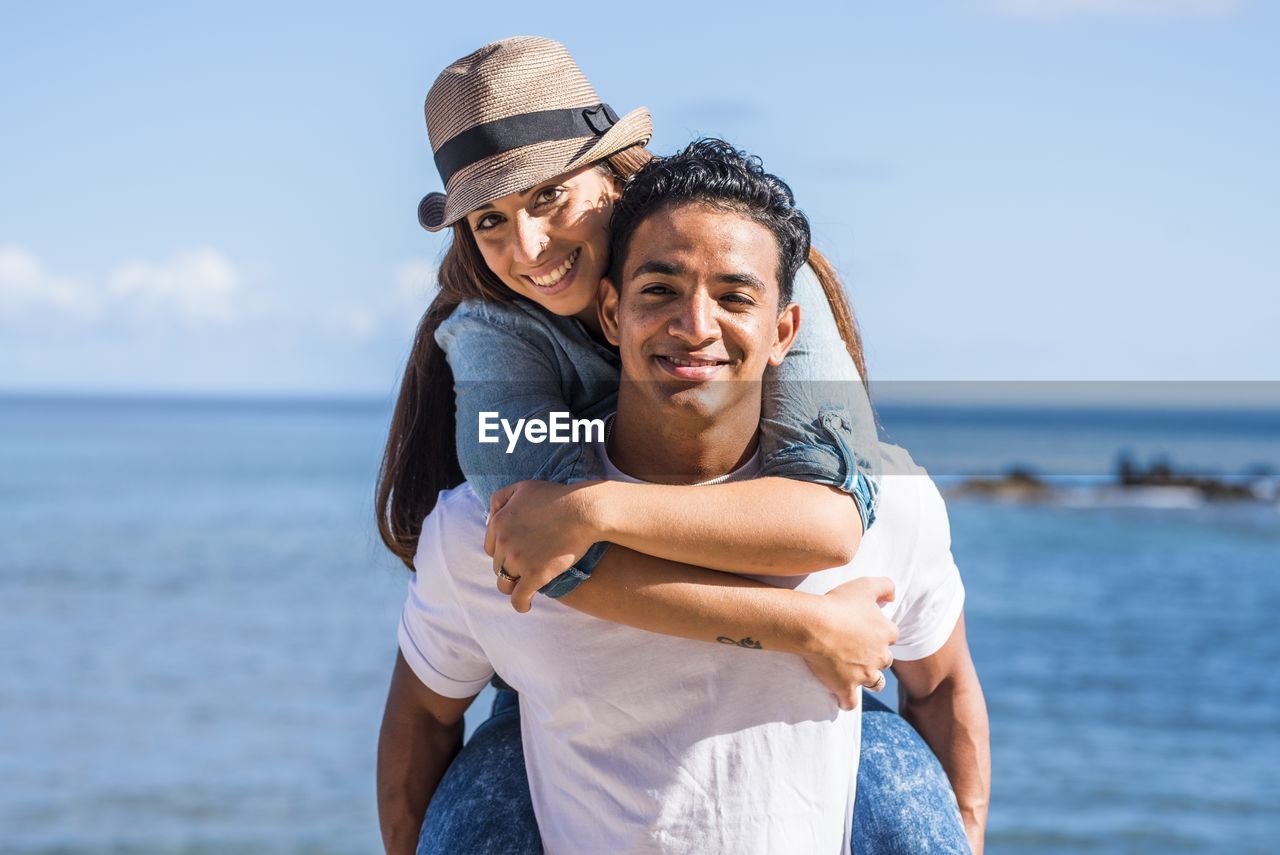 Portrait of happy friends at beach against sky