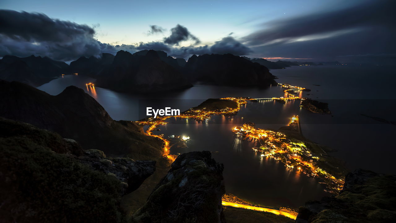 SCENIC VIEW OF ILLUMINATED MOUNTAINS AGAINST SKY AT SUNSET