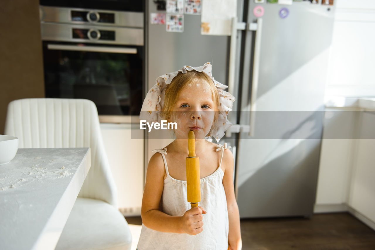 Little girl cooking pizza in the kitchen