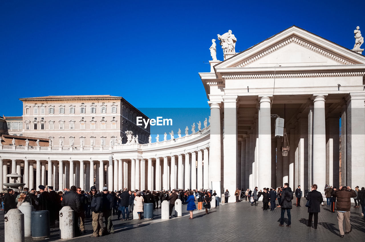 People at st peters square in city against clear blue sky