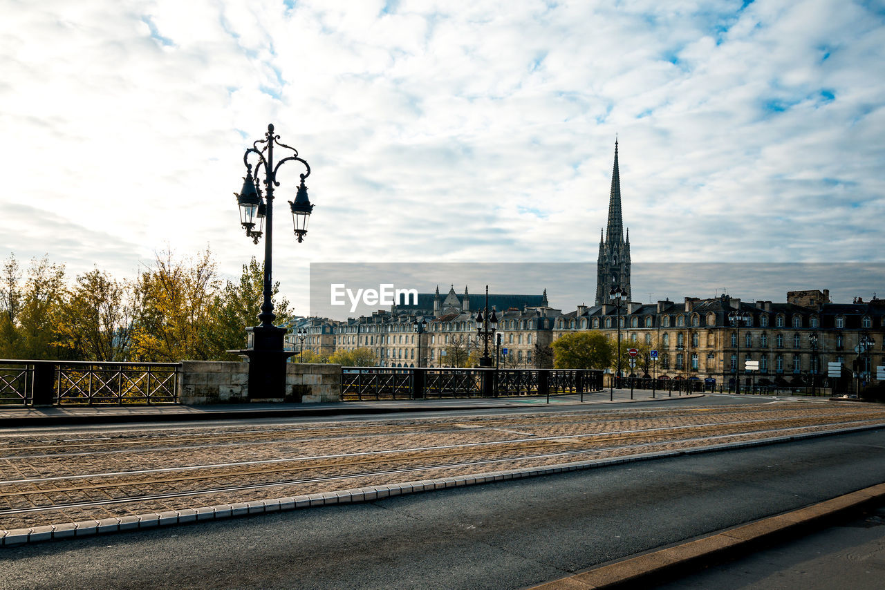 Street by historic church against cloudy sky in city