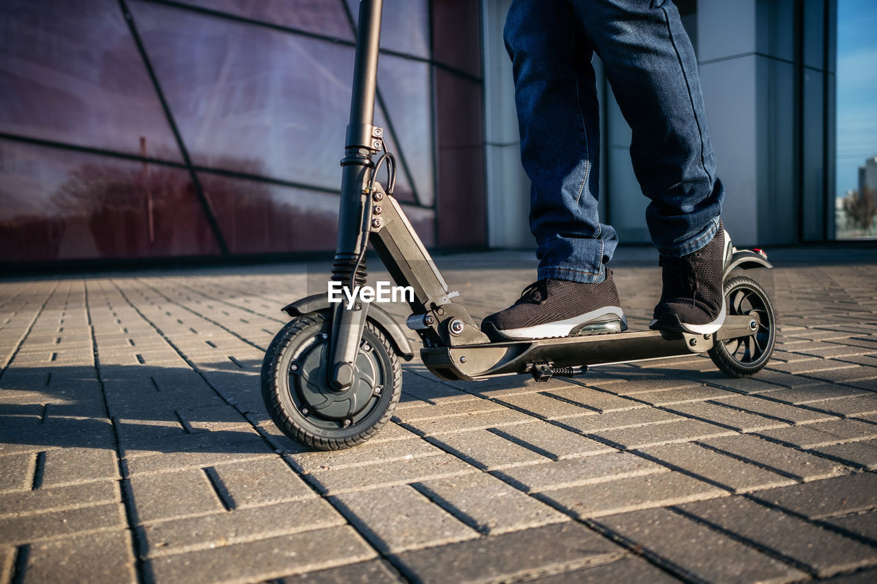 Low section of man with push scooter on footpath