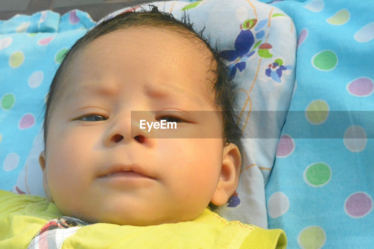 CLOSE-UP PORTRAIT OF CUTE BABY GIRL LYING ON BED