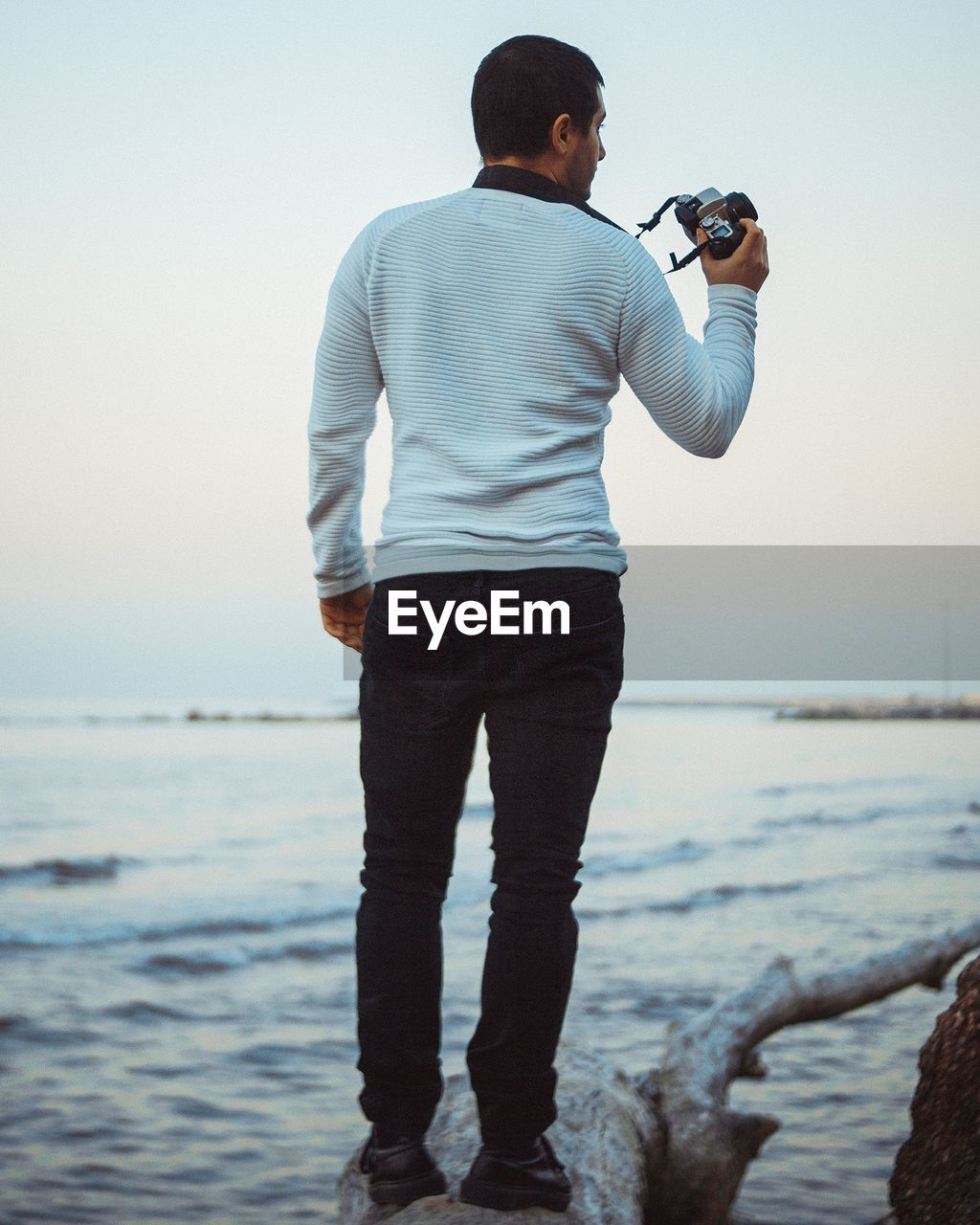 Rear view of man photographing at beach