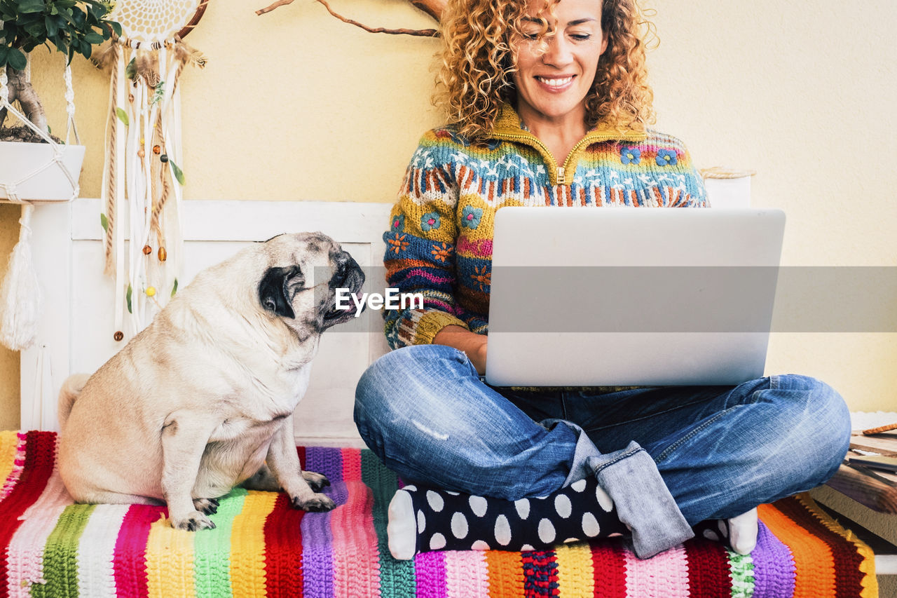 portrait of woman using laptop while sitting on sofa at home