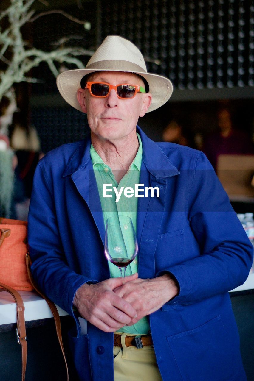 Portrait of senior man wearing sunglasses standing by table