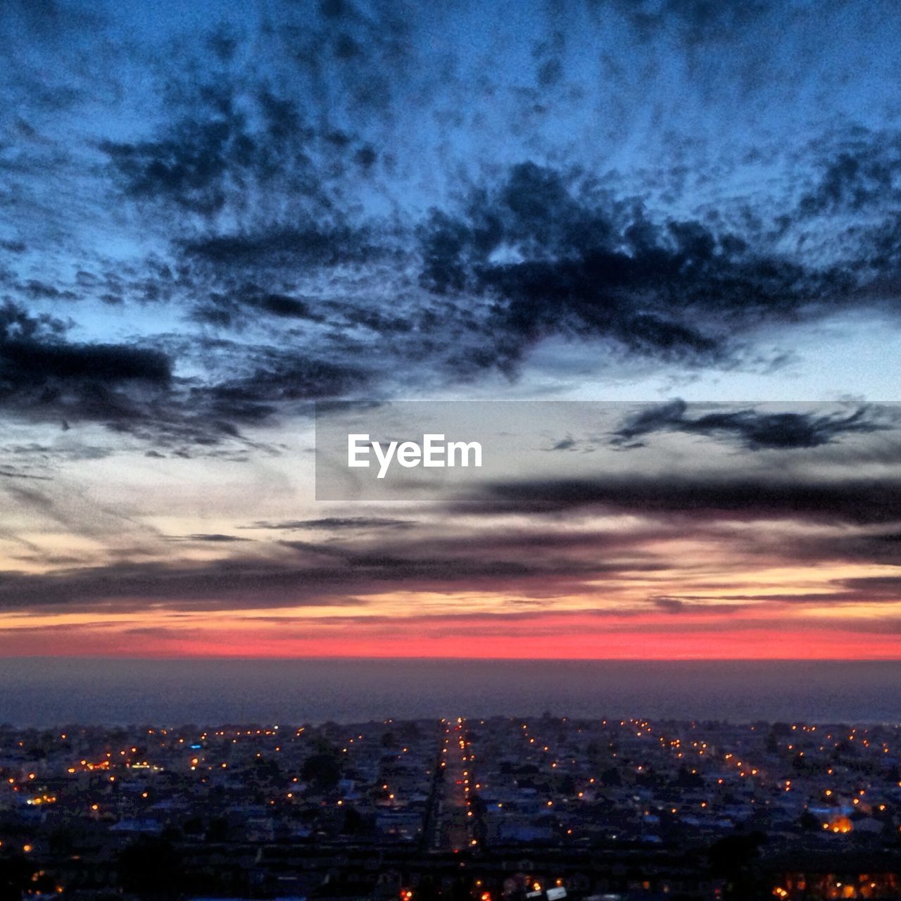 Scenic view of illuminated residential district against cloudy sky