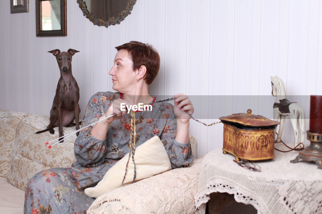 Woman weaving crochet while sitting on sofa at home